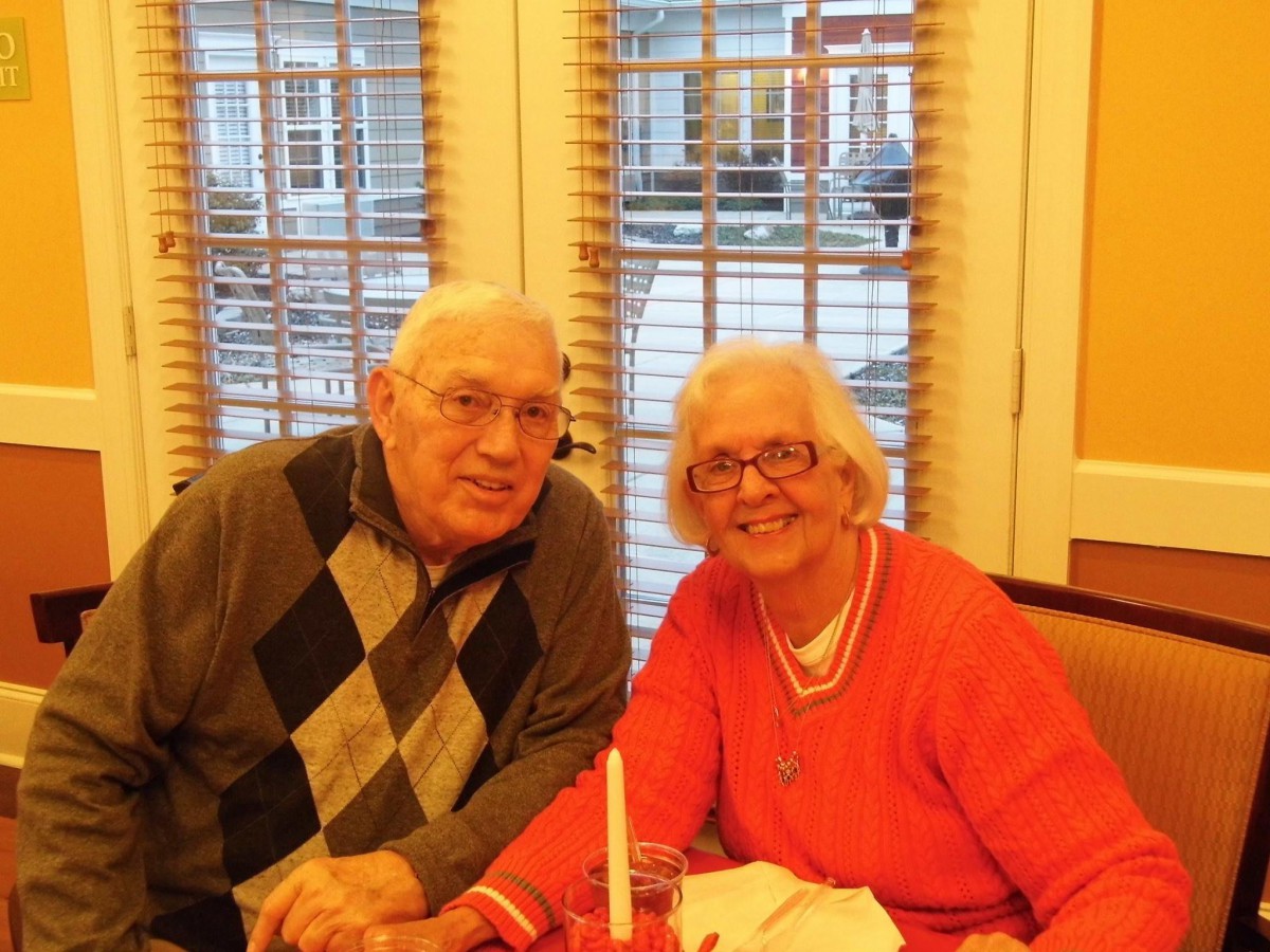 An elderly couple enjoying a meal together inside a cozy setting.