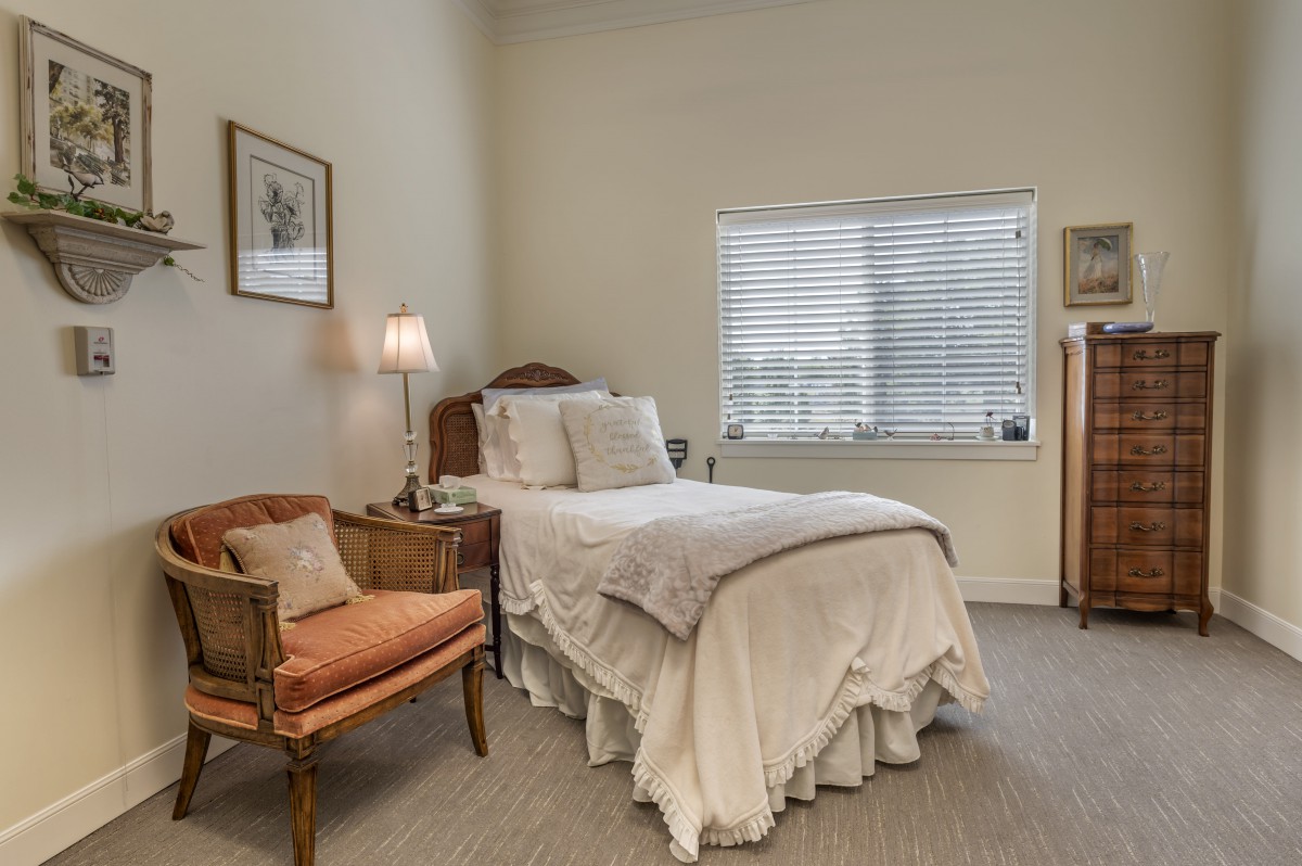 A cozy bedroom with a single bed and an armchair near the window.