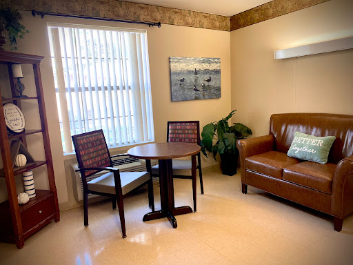 A cozy living room setup featuring a comfortable sofa, a small table with chairs, and decorative artwork on the wall.