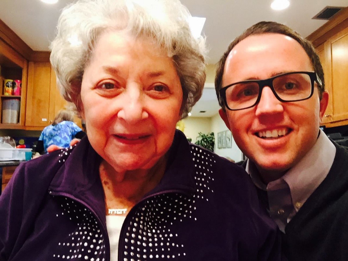 An elderly woman and a man taking a selfie together indoors.