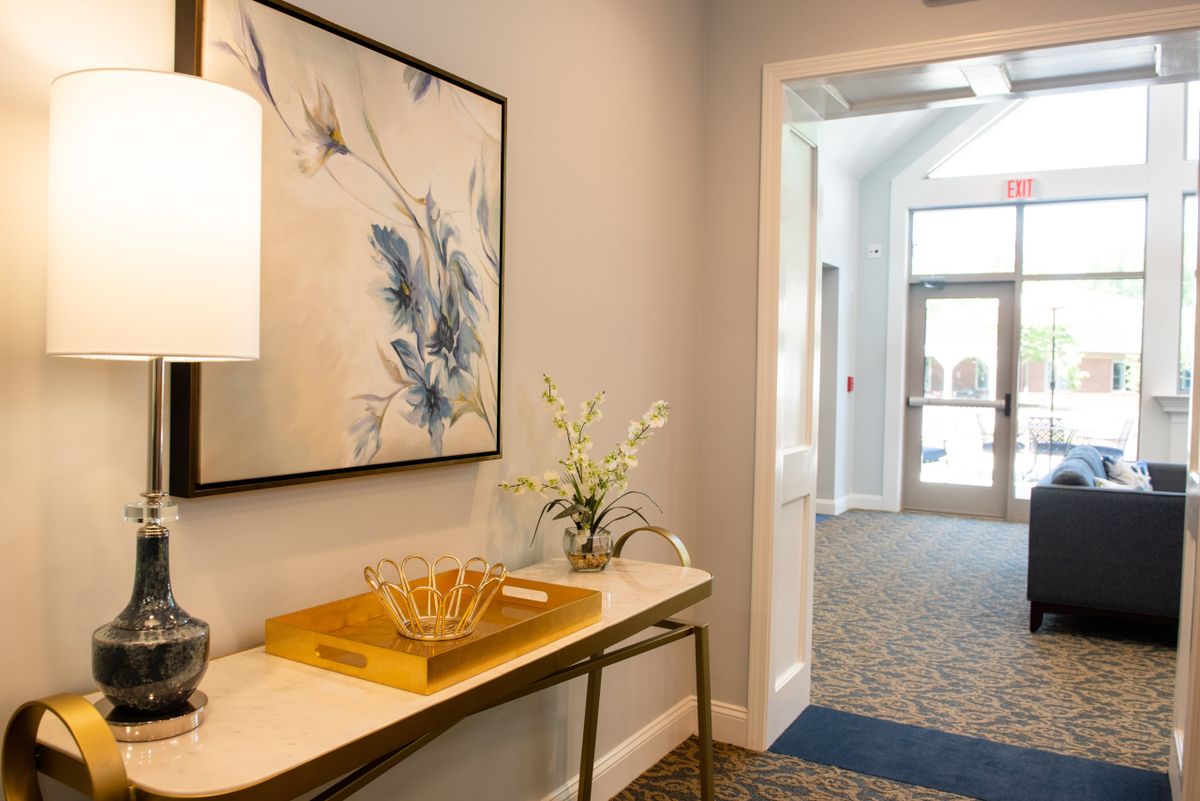A modern hallway with elegant decor featuring a floral artwork, a vase with flowers, and a stylish table.