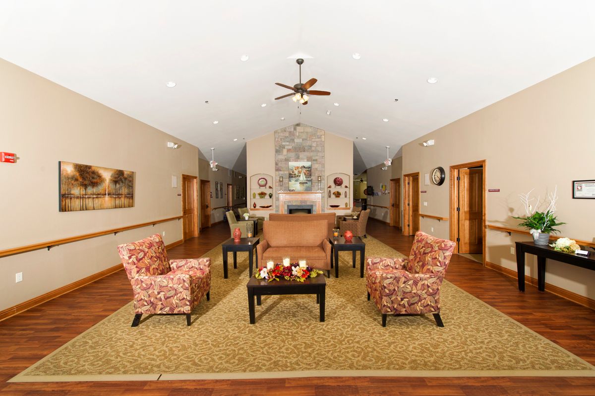 A cozy and elegantly designed living area featuring stylish armchairs, a sofa, and a central coffee table, accentuated by warm lighting and modern decor.