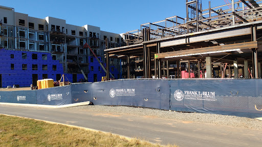 A construction site featuring a steel framework with blue tarps, indicating ongoing development.