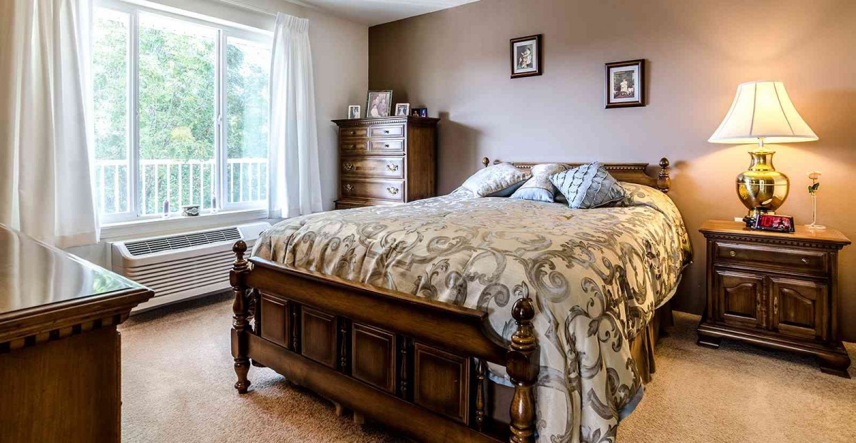 A cozy bedroom with a wooden bed and chest of drawers.