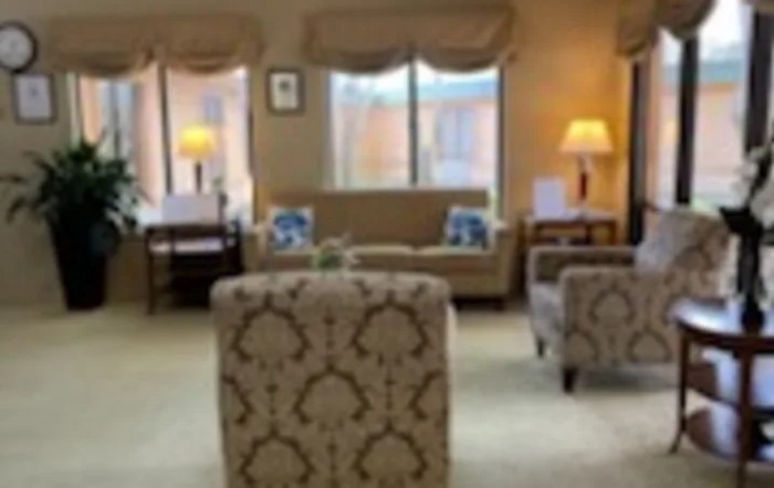 A cozy living room with comfortable seating, lamps, and large windows.