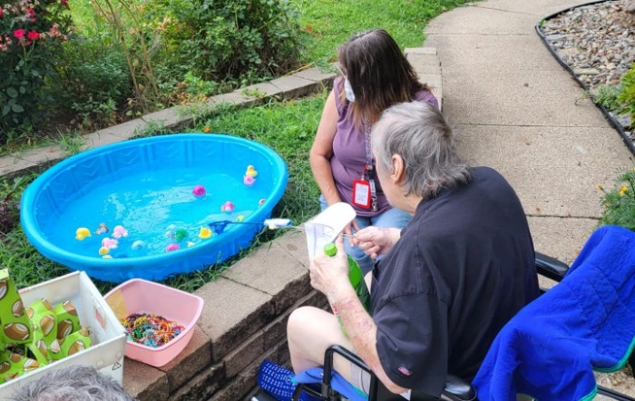 Two people engaging in outdoor activities next to a small pool filled with toys.
