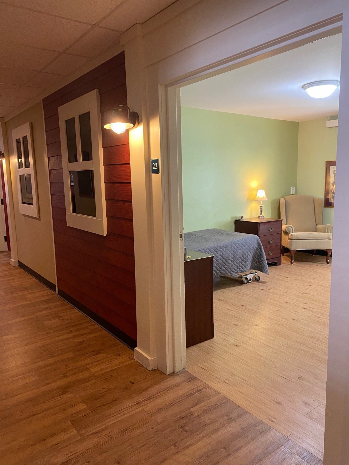 A cozy hallway leading to a warmly lit bedroom with wood flooring.