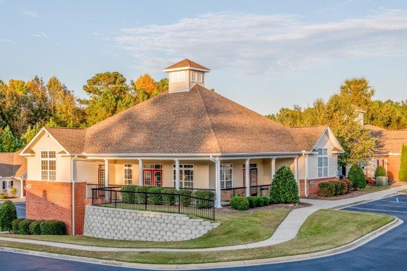 A suburban residential building with a sloped roof and surrounding trees.