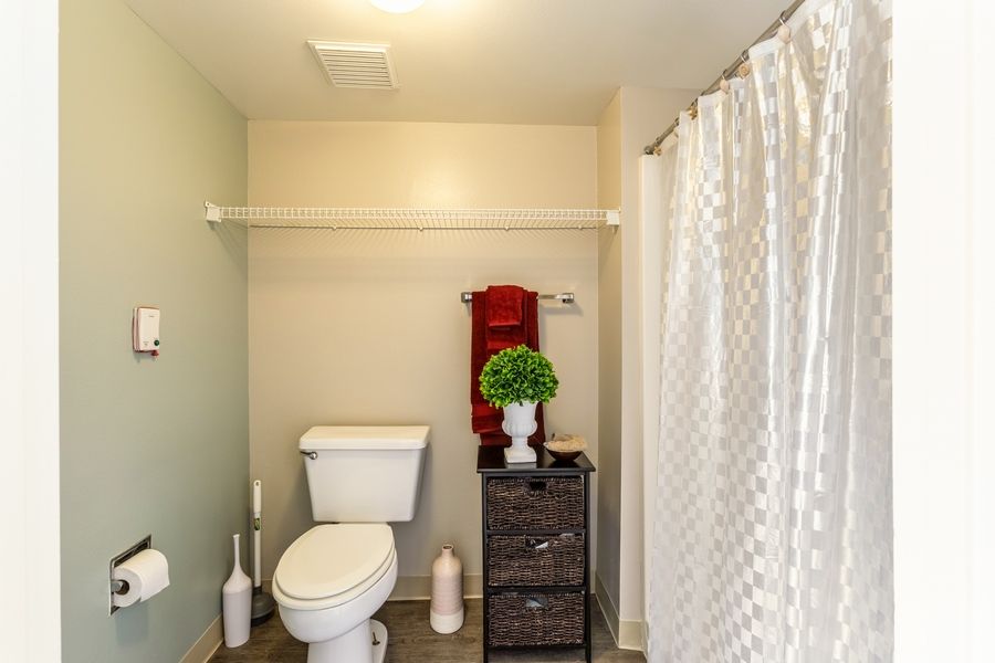 A neatly organized bathroom with a white shower curtain and decorative elements.