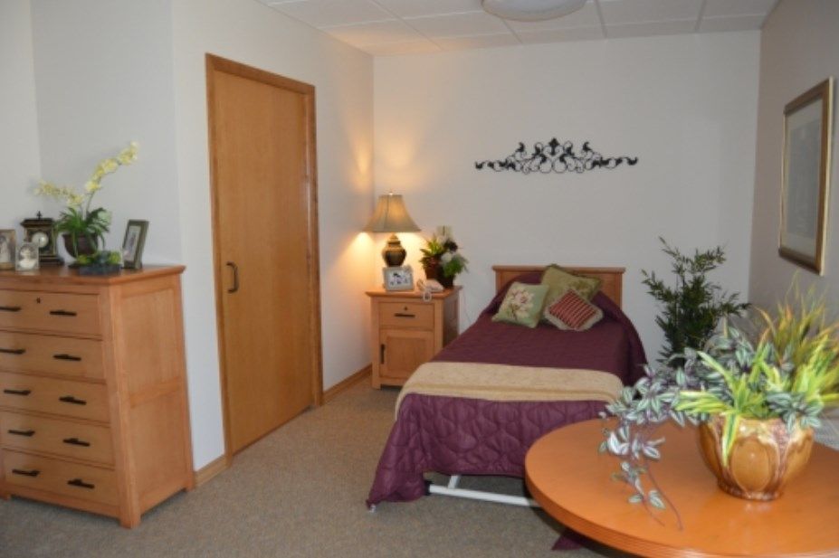 A cozy bedroom featuring a single bed with pillows, a nightstand with a lamp, and decorative elements.