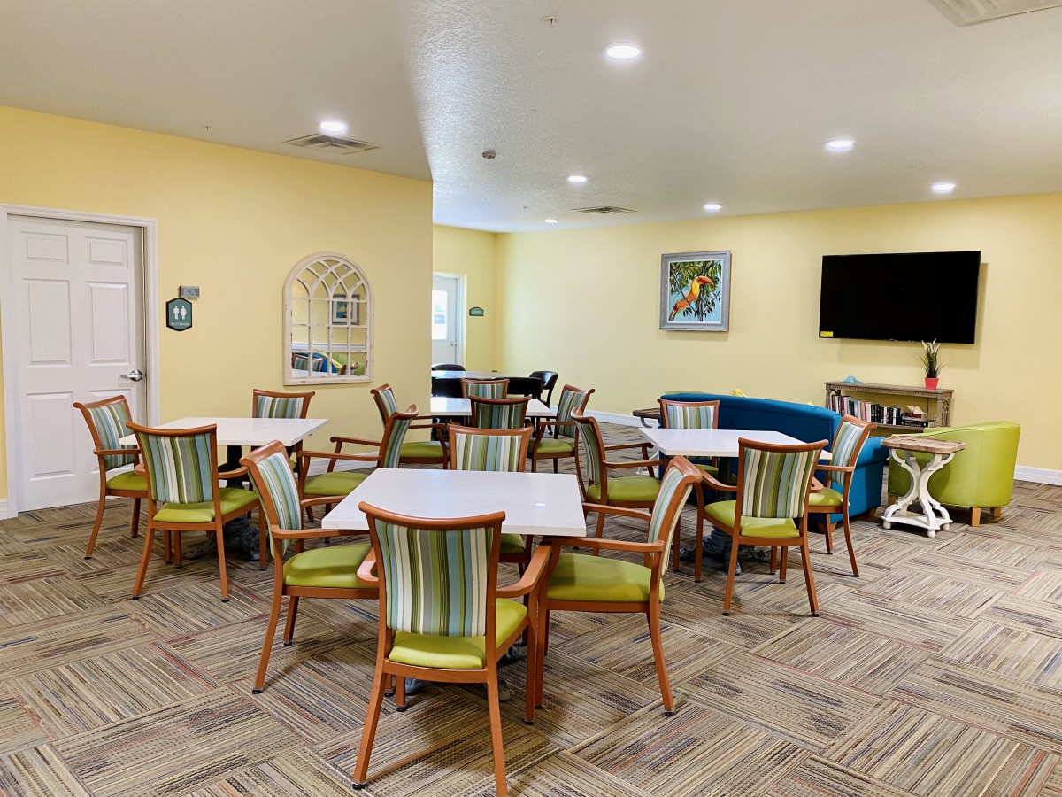 A bright and welcoming dining area with multiple tables and chairs, featuring a television and wall decorations.