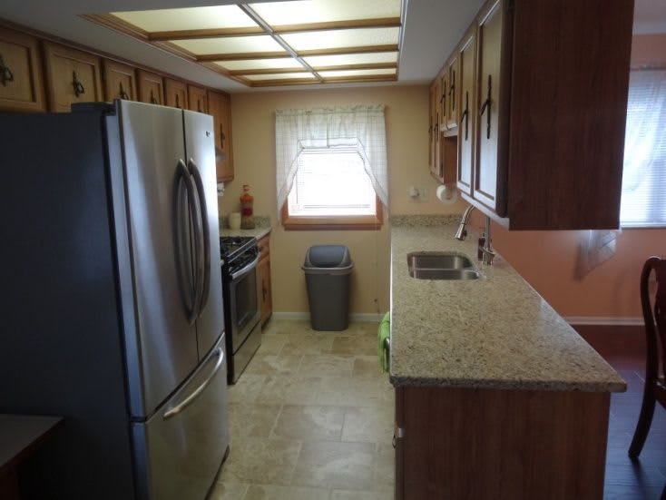 A modern kitchen with wooden cabinets, stainless steel appliances, and a window providing natural light.