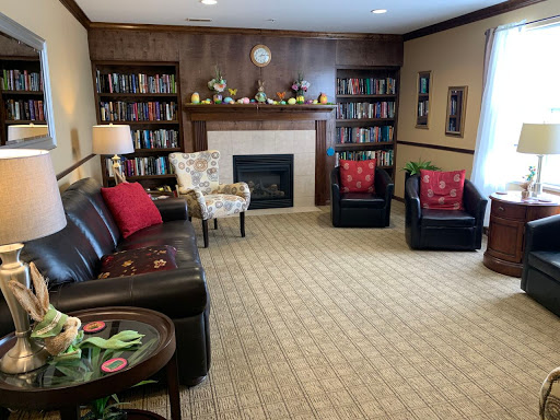 A cozy living room featuring comfortable seating, a fireplace, and an extensive bookshelf.