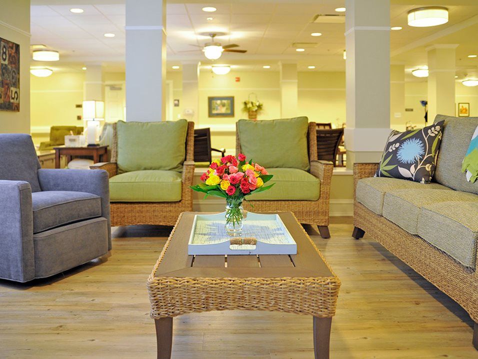 A cozy living room with comfortable seating, featuring a wicker coffee table adorned with a flower arrangement.