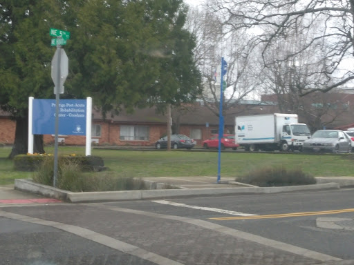 A view of a building with a sign, featuring parked vehicles including a truck.