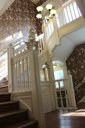 A beautifully designed interior staircase featuring elegant woodwork and floral wallpaper.