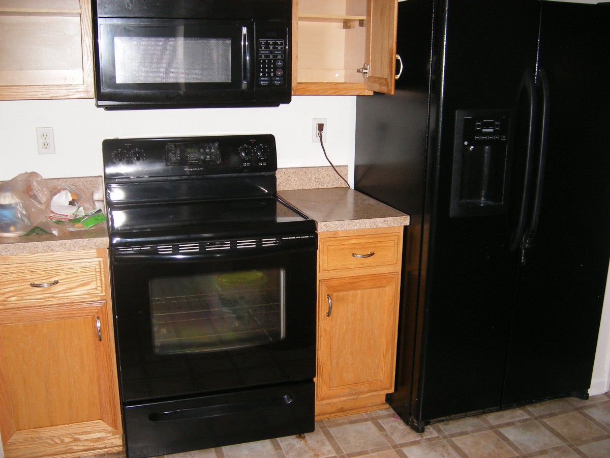 A kitchen setup featuring black appliances including an oven, microwave, and refrigerator alongside wooden cabinets.