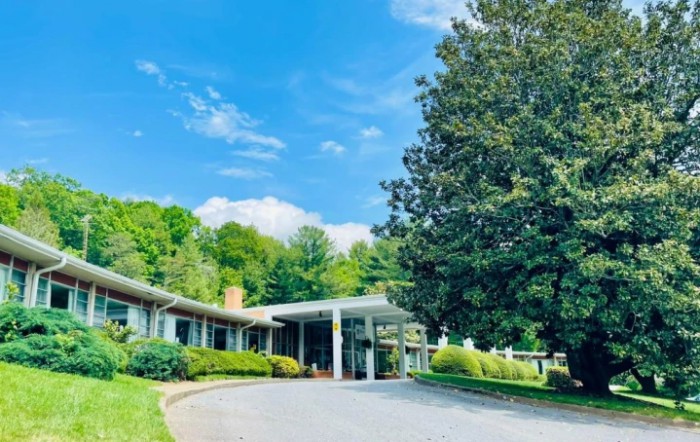 A serene view of a building surrounded by lush greenery and a clear blue sky.