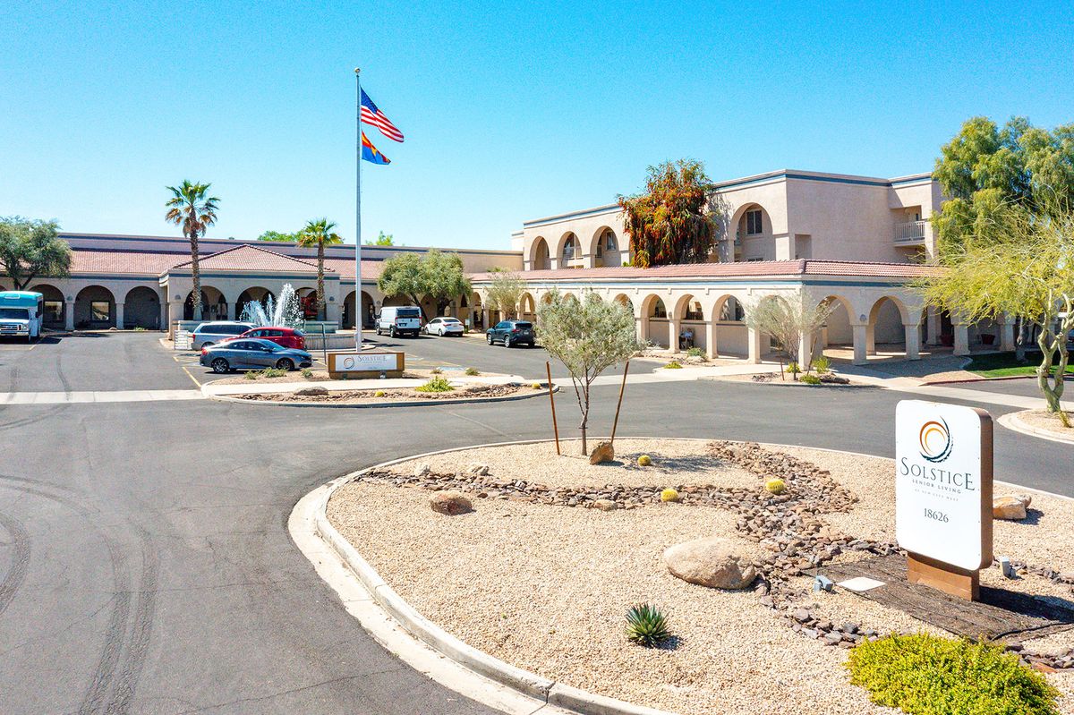 A building with an arched facade and a surrounding parking lot, set in a desert landscape with a prominent flagpole.