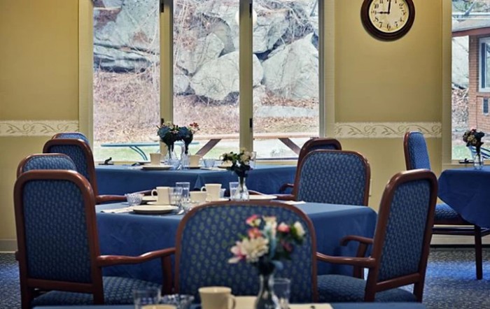 An elegantly set dining room with tables and chairs, featuring a view of the outside through large windows.