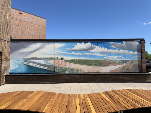 A vibrant mural depicting a serene coastal landscape under a blue sky with clouds.
