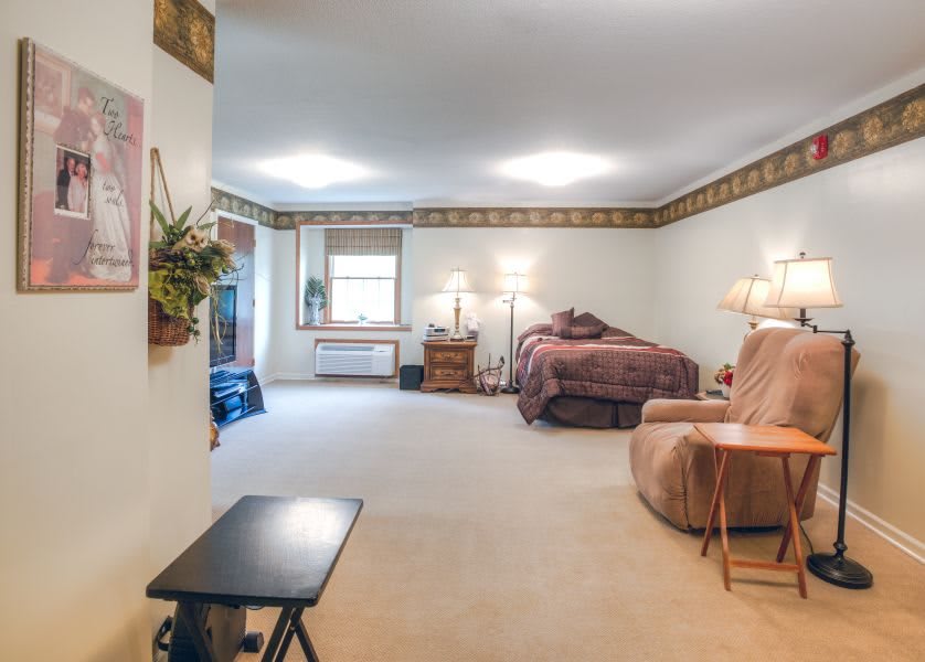 A cozy living space with a blend of living room and bedroom elements, featuring comfortable furniture, lamps, and decorative accents.