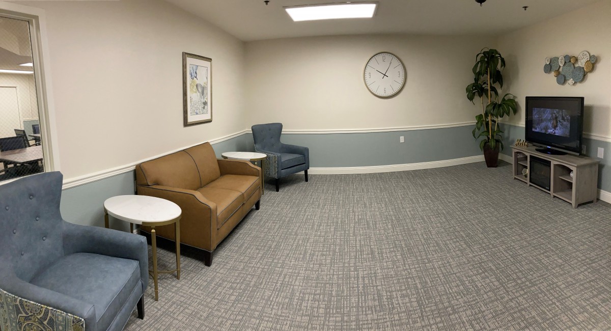 A quiet waiting room with a sofa, armchair, and clock on the wall.