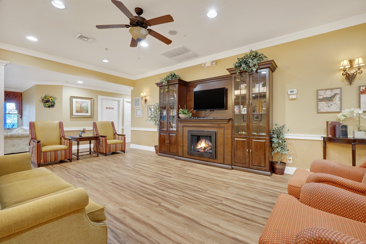 A cozy living room with a fireplace, wooden entertainment center, and ceiling fan.