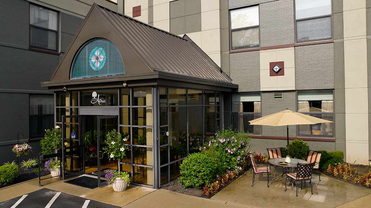 The entrance of a hotel with outdoor seating and lush greenery.