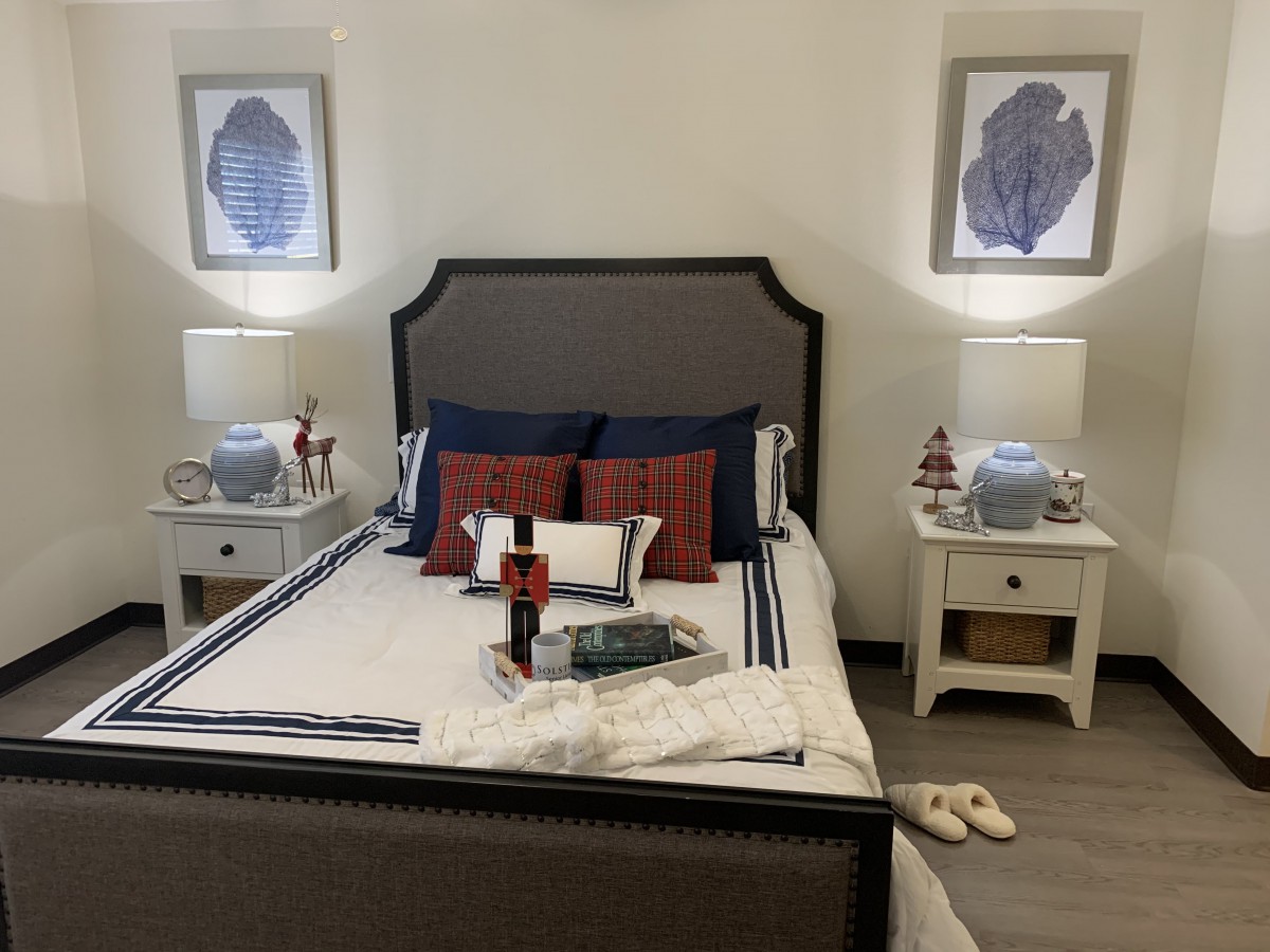 A neatly arranged bedroom featuring a bed with pillows and a comforter, flanked by nightstands with lamps and decorative items.