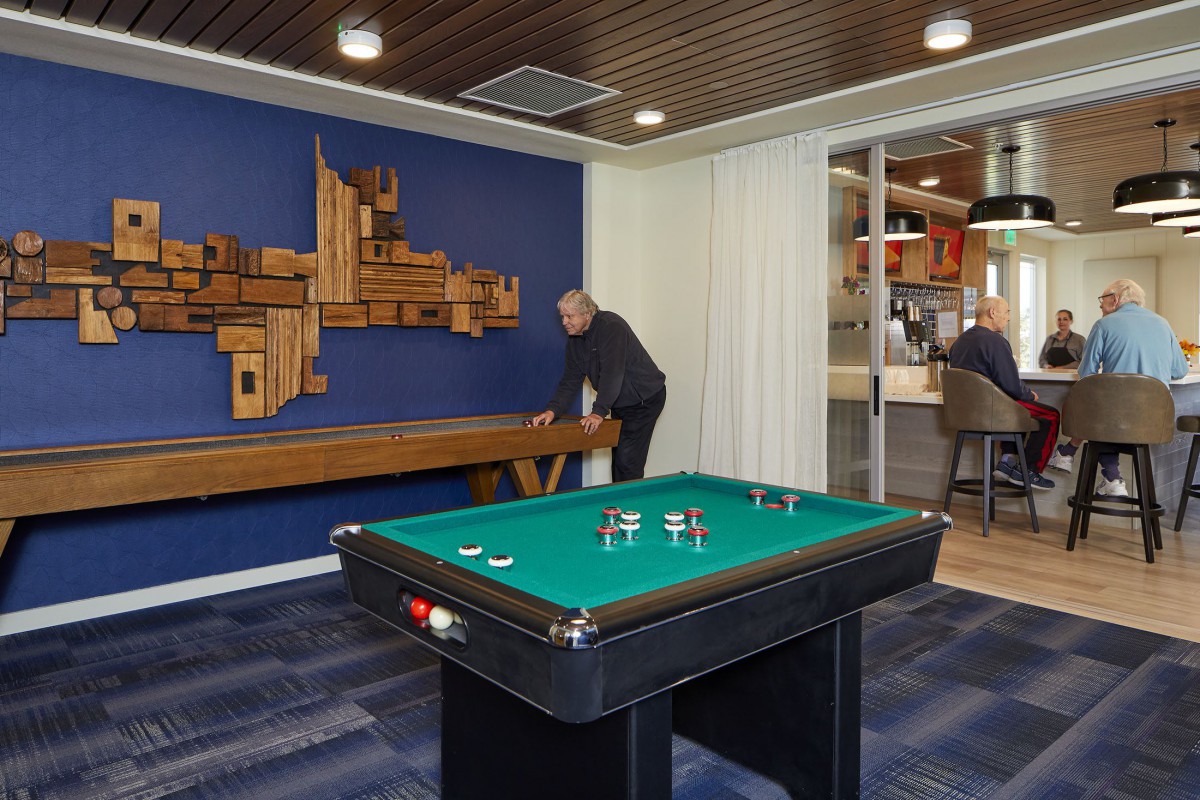 A modern game room featuring a pool table and shuffleboard with stylish interior design.