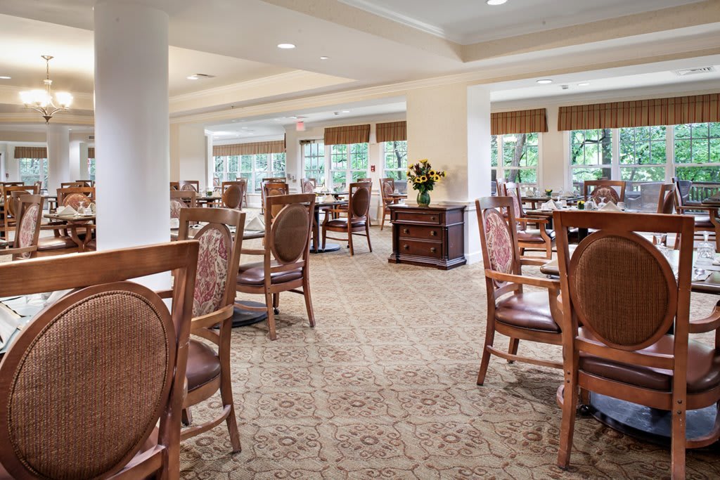 A well-lit dining area with elegant wooden furniture and large windows.