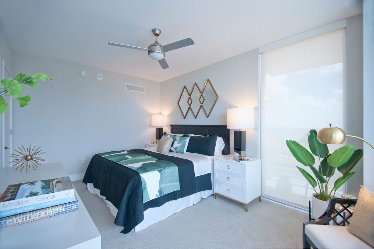 A modern bedroom with stylish decor, featuring a neatly made bed, nightstands with lamps, and geometric mirrors on the wall.