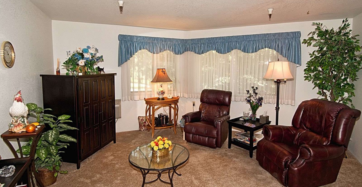 A cozy living room with a recliner chair, side tables with lamps, and a glass coffee table.