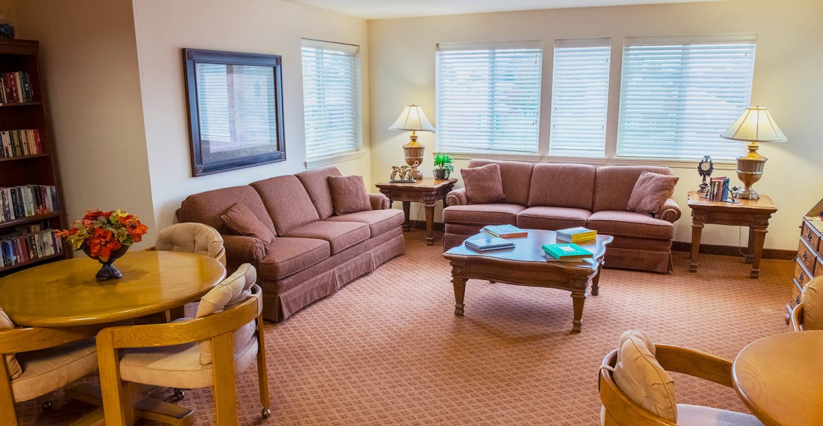 A cozy living room with two sofas, a coffee table, and a lamp by the window.