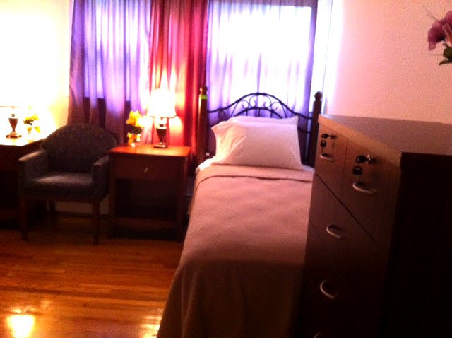 A cozy bedroom with a single bed, side table, and dresser.