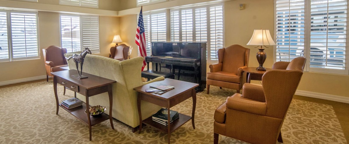 A cozy living room with a piano, armchairs, and an American flag.