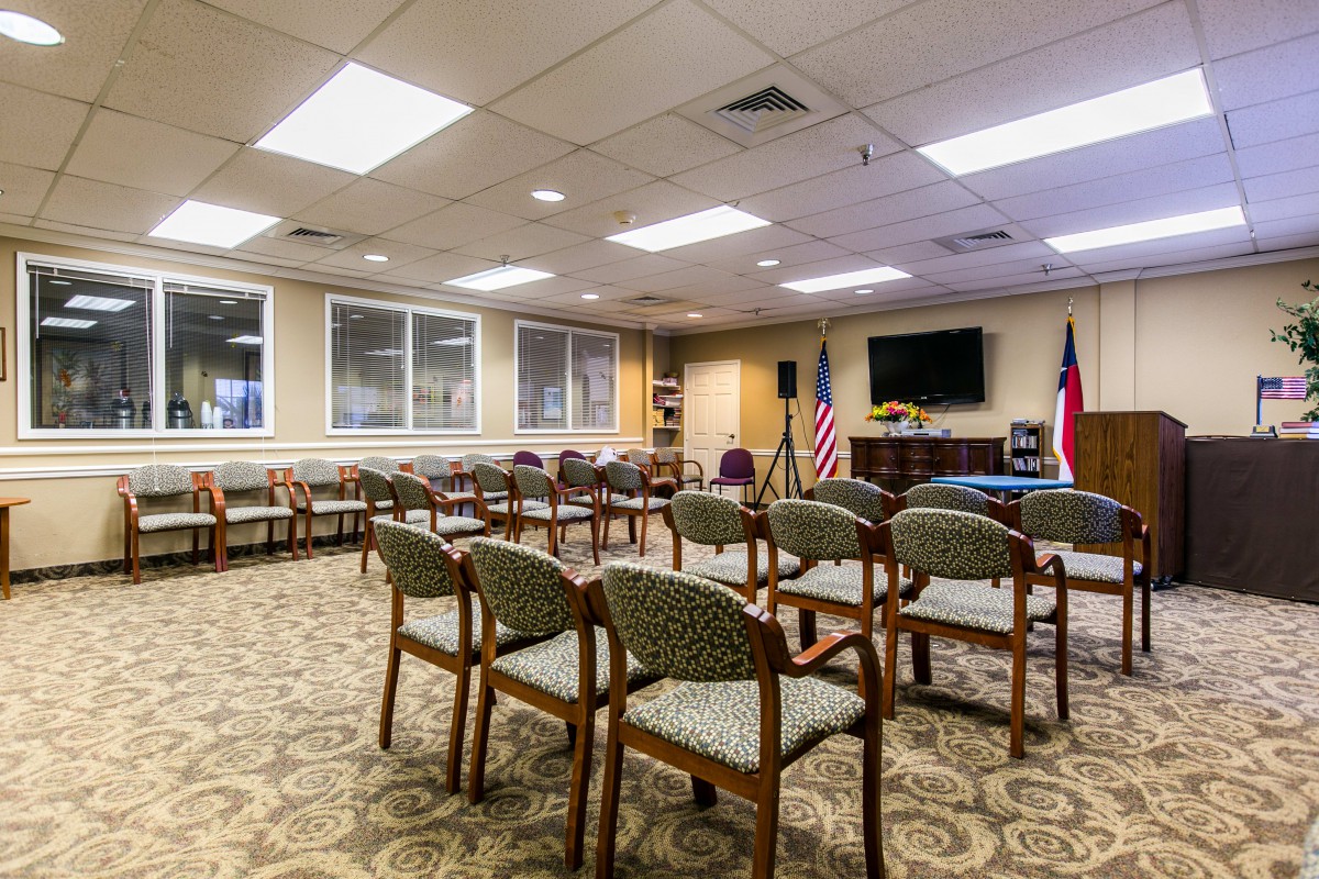 A conference room set up with chairs facing a television and flags, ready for a meeting or event.