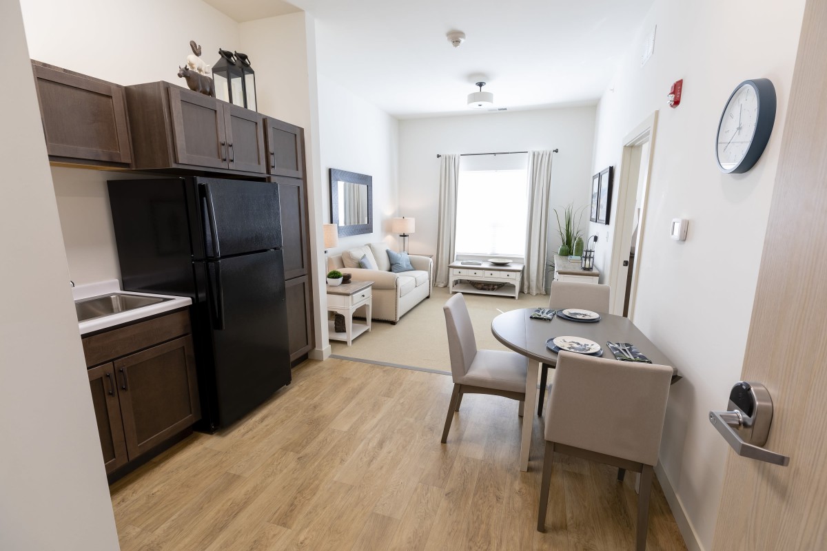A modern apartment interior featuring a kitchen, dining area, and living room with contemporary furnishings.
