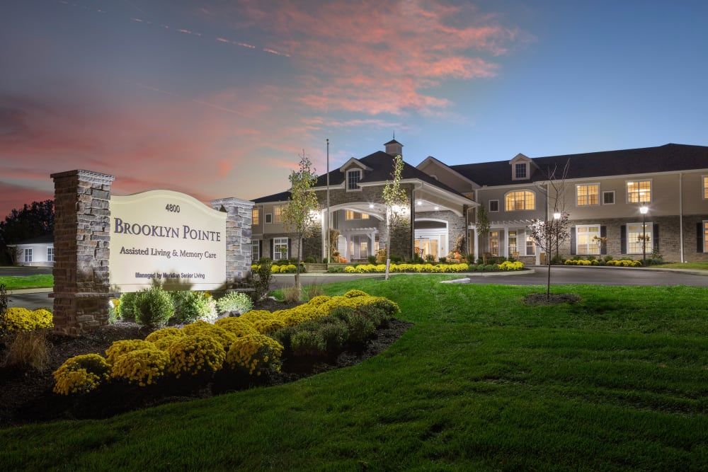 A beautifully lit building at dusk with well-manicured landscaping and a prominent sign in the foreground.