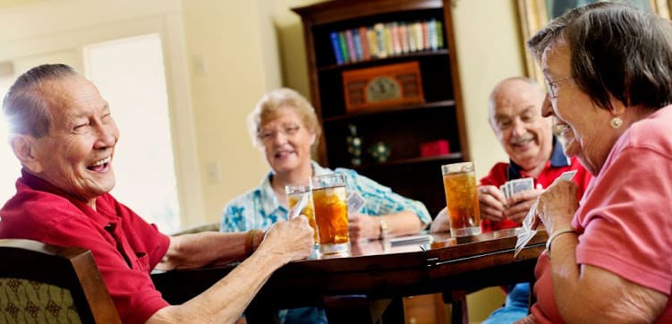 A group of seniors enjoying drinks and conversation at a table indoors.