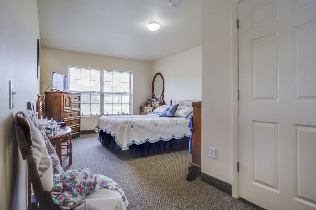 A cozy bedroom with a large window, bed, and wooden furniture.