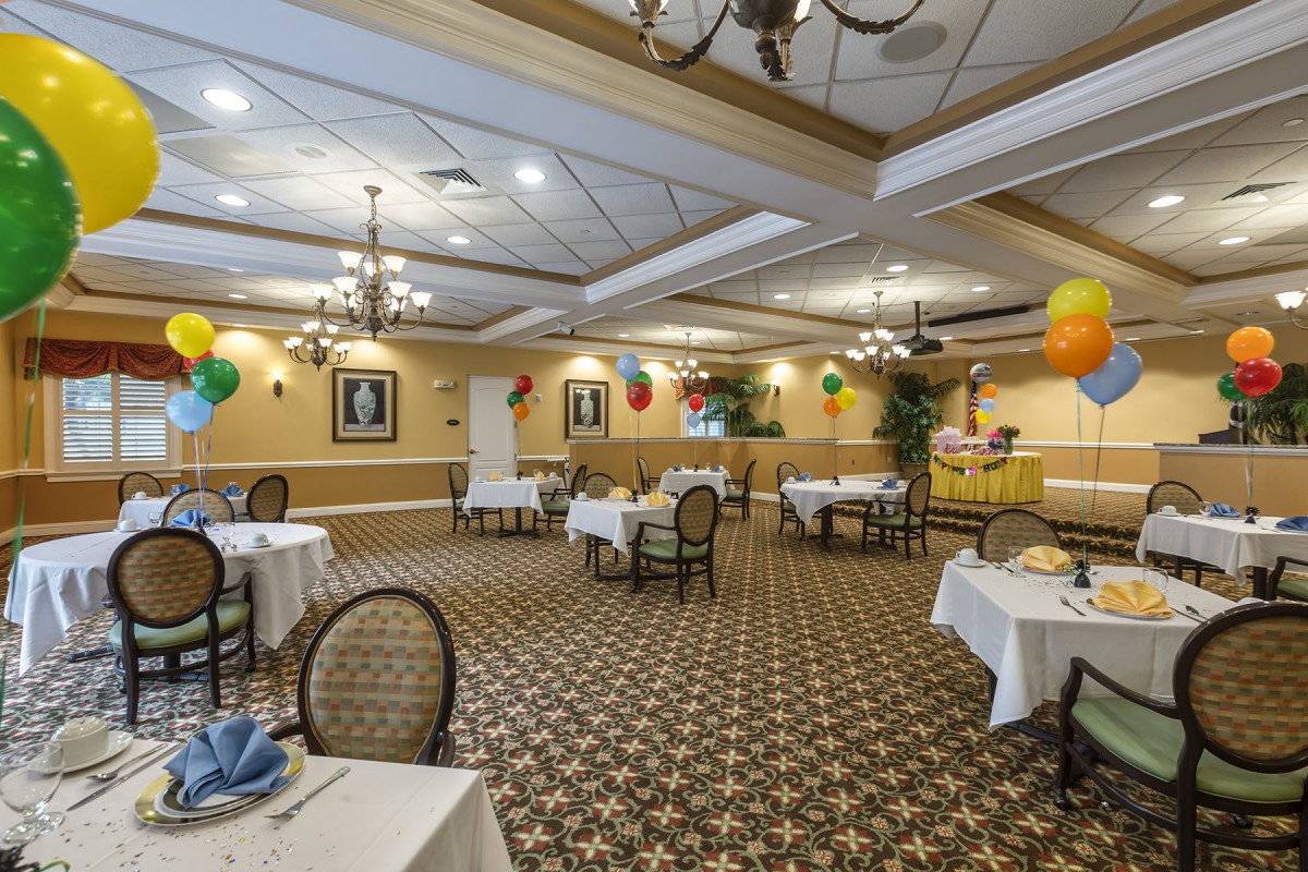 A decorated dining room with tables, chairs, and colorful balloons.