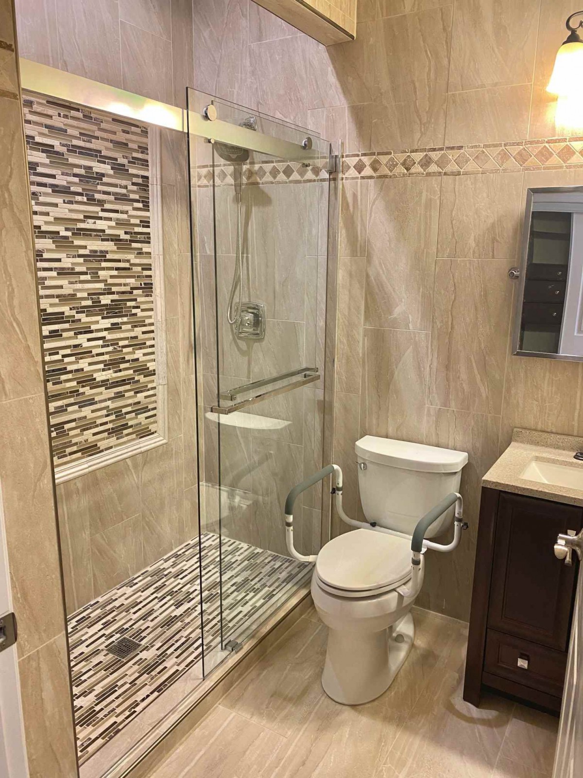 A modern bathroom with a glass shower enclosure and tiled walls.