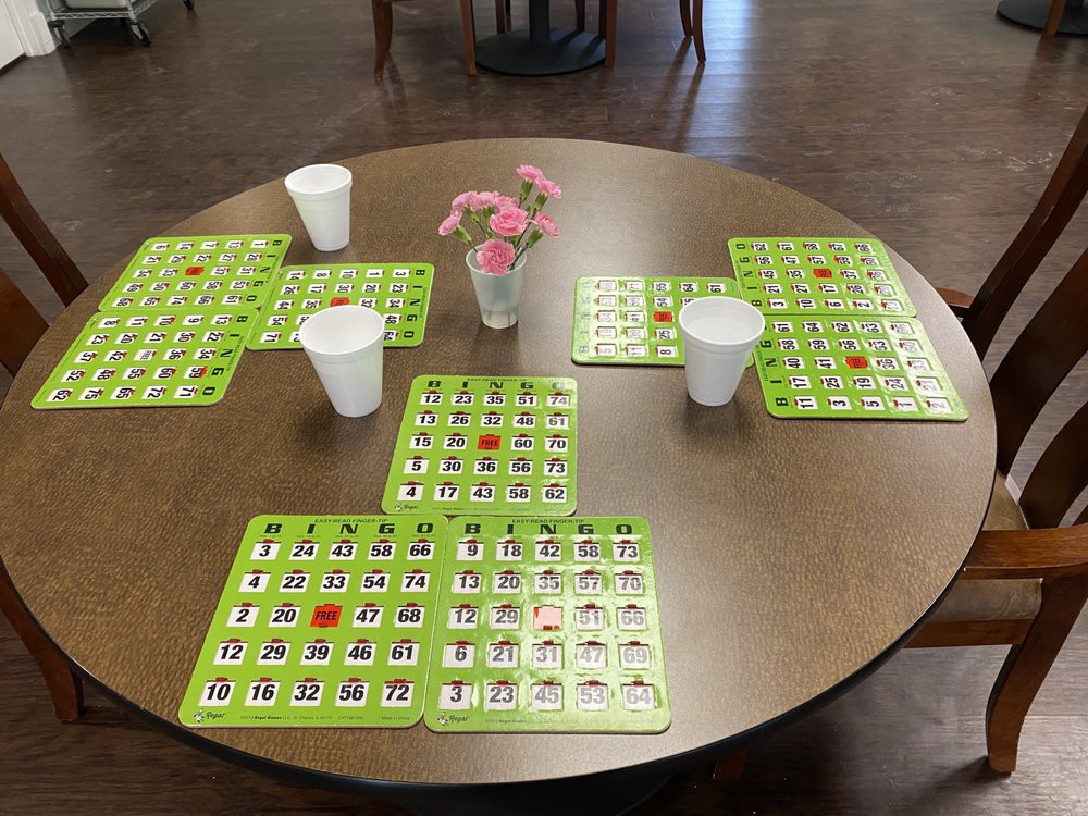 A table set up for a game of bingo with green cards and cups.