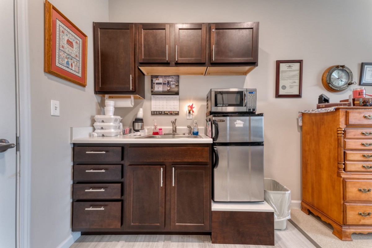 Compact kitchenette with dark brown cabinets, a mini fridge, and a microwave.