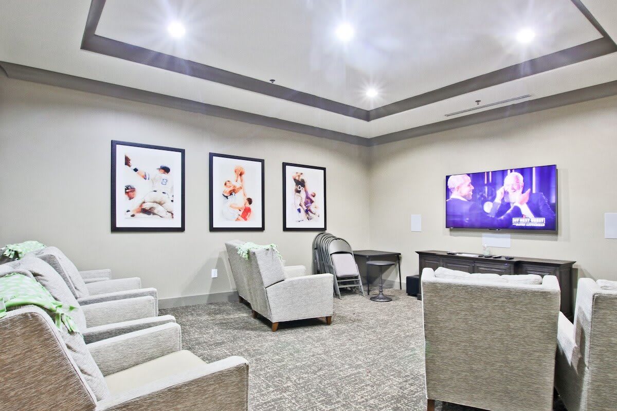 A modern conference room with comfortable seating and a large screen, decorated with contemporary artwork.