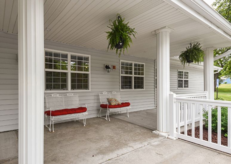 A cozy porch area with swing benches, hanging plants, and a white railing.