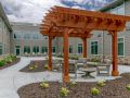 A wooden pergola providing shade over outdoor seating in a landscaped patio area.