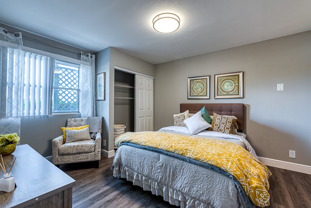 A modern and cozy bedroom featuring stylish decor with a comfortable bed, an armchair, and framed artwork.